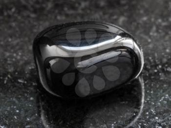 macro shooting of natural mineral rock specimen - polished black Onyx gemstone on dark granite background