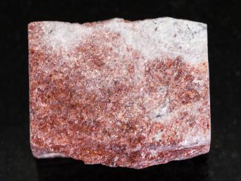 macro shooting of natural mineral rock specimen - rough pink Aventurine stone on dark granite background from Verkhneye Dubrovo district of Sverdlovk region, Ural Mountains, Russia