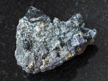 macro shooting of natural mineral rock specimen - Molybdenite crystal with pyrite and Magnetite in raw Glaucophane stone on dark granite background from Kalgutinskoye mine in Altai Mountains, Russia