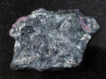 macro shooting of natural mineral rock specimen - raw aegirine stone on dark granite background from Irkutsk region, Russia