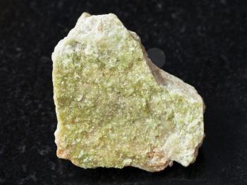 macro shooting of natural mineral rock specimen - green Vesuvianite crystals on raw stone on dark granite background from Yakutia, Siberia, Russia