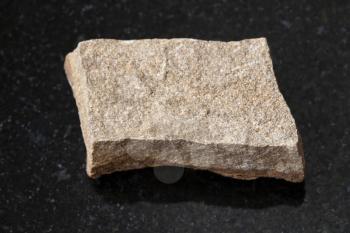 macro shooting of natural mineral rock specimen - raw polymictic sandstone stone on dark granite background