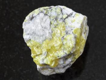 macro shooting of natural mineral rock specimen - rough sulfur ore on dark granite background from Volodinskoye mine, Samara region, Russia