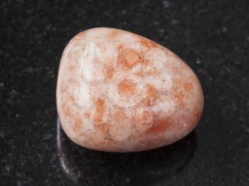 macro shooting of natural mineral rock specimen - polished sunstone (heliolite) gem stone on dark granite background from USA