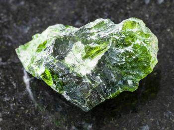 macro shooting of natural mineral rock specimen - rough crystal of Chrome Diopside gemstone on dark granite background from Inagli (Inaglinskoe mine) in Yakutia, Siberia, Russia