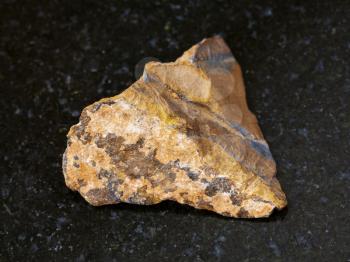 macro shooting of natural mineral rock specimen - raw tiger-eye stone on dark granite background from South Africa