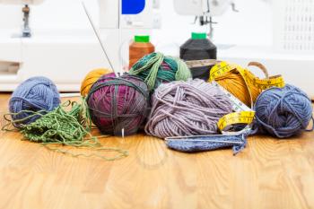 needlework still life - knitting tools, threads on table and sewing machines on background