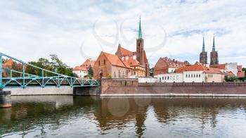 travel to Poland - view of pedestrian Tumski Bridge (Most Tumski) and Collegiate Church of the Holy Cross and St Bartholomew in Ostrow Tumski district in Wroclaw city from Oder River