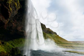 travel to Iceland - cave and Seljalandsfoss waterfall of Seljalands River in Katla Geopark on Icelandic Atlantic South Coast in september