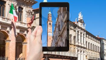 travel concept - tourist photographs clock tower (torre della bissara) of Basilica Palladiana in Vicenza city in Italy on tablet