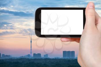 travel concept - tourist photographs Moscow city skyline with Ostankinskaya TV Tower in Russia in sunrize on smartphone with cut out screen for advertising logo