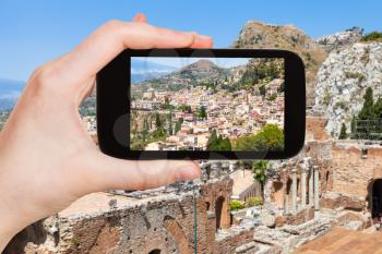 travel concept - tourist photographs Taormina city on slope of cape in Sicily Italy in summer on smartphone
