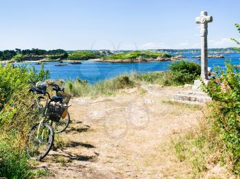 travel to France - tourist bicycle at viewpoint near Celtic cross on Ile-de-Brehat island in Cotes-d'Armor department of Brittany in summer sunny day