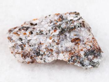 macro shooting of natural mineral rock specimen - brown chondrodite and green diopside crystals in raw calcite stone on white marble background from Pitkyaranta region of Karelia, Russia