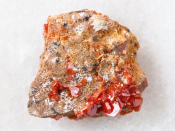 macro shooting of natural mineral rock specimen - rough crystals of Vanadinite on stone on white marble background from Morocco