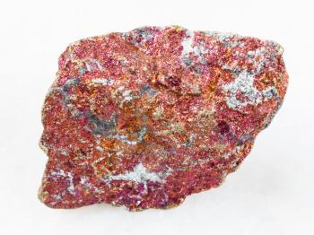 macro shooting of natural mineral rock specimen - raw red Chalcopyrite stone on white marble background from Mexico