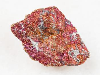 macro shooting of natural mineral rock specimen - rough red Chalcopyrite stone on white marble background from Mexico