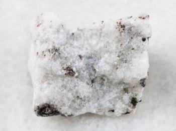 macro shooting of natural mineral rock specimen - rough carbonatite stone on white marble background