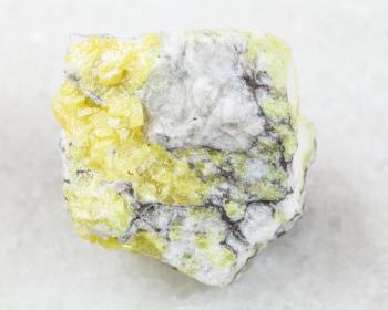 macro shooting of natural mineral rock specimen - raw sulfur ore on white marble background from Volodinskoye mine, Samara region, Russia