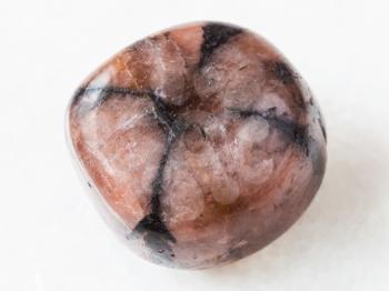 macro shooting of natural mineral rock specimen - polished Chiastolite gemstone on white marble background