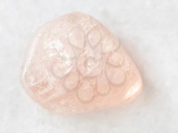 macro shooting of natural mineral rock specimen - polished morganite (pink beryl) gemstone on white marble background from Ural Mountains, Russia