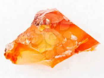 macro shooting of natural mineral rock specimen - rough crystal of cornelian (red chalcedony, sard) gemstone on white marble background from Zeya River region in the Russian Far East