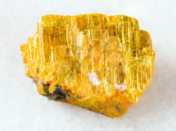 macro shooting of natural mineral rock specimen - raw native orpiment stone on white marble background from Yakutia, Russia