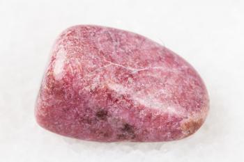 macro shooting of natural mineral rock specimen - polished rhodonite gem on white marble background from Ural Mountains