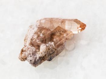 macro shooting of natural mineral rock specimen - raw crystal of topaz gemstone on white marble background from Brazil