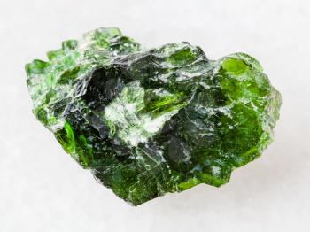 macro shooting of natural mineral rock specimen - rough crystal of Chrome Diopside gemstone on white marble background from Inagli (Inaglinskoe mine) in Yakutia, Siberia, Russia