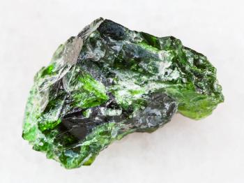 macro shooting of natural mineral rock specimen - green crystal of Chrome Diopside gemstone on white marble background from Inagli (Inaglinskoe mine) in Yakutia, Siberia, Russia
