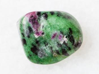 macro shooting of natural mineral rock specimen - polished zoisite (anyolite) gemstone on white marble background