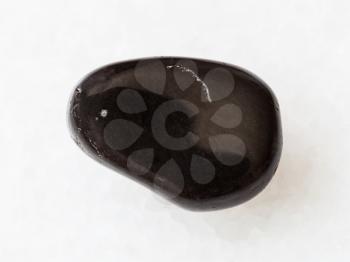 macro shooting of natural mineral rock specimen - polished black obsidian gem stone on white marble background from Mexico