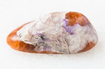macro shooting of natural mineral rock specimen - charoite in polished Tinaksite gemstone on white marble background from Murun Massif, Yakutia, Russia
