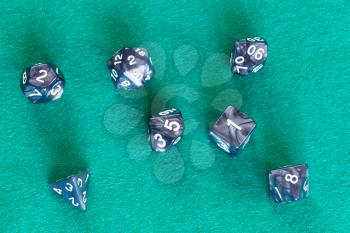 set of gray polyhedral dices for Dungeons and Dragons board game playing on green baize table