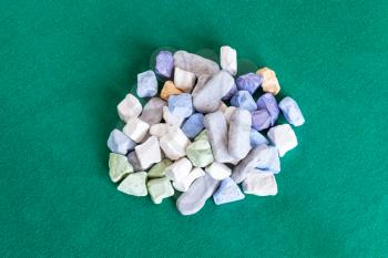 top view of pile of various multicolored stones on green baize table