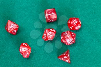 set of red polyhedral dices for Dungeons and Dragons board game playing on green baize table