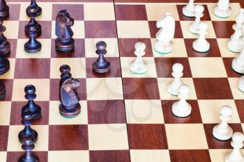 side view of chess gameplay on wooden chessboard close up
