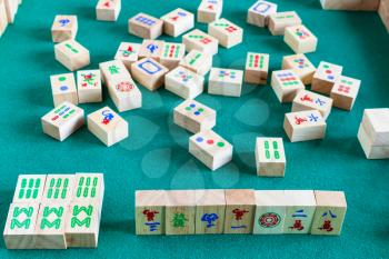 gameplay of mahjong game, tile-based chinese strategy board game on green baize table