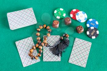 top view of card decks, wooden dices, casino tokens and worry beads on green table