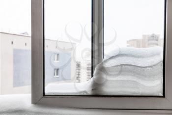 view through window with snowdrift between frames in Moscow city in winter