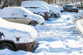 snow-covered cars on car parking in Moscow city in sunny winter day