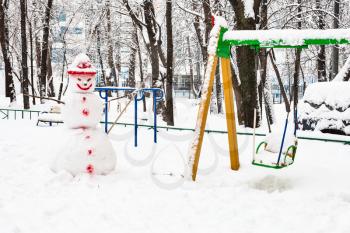 snowman at public playground in residential district of Moscow city in overcast winter day