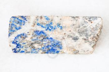 macro shooting of natural mineral - rod from Lazurite stone on white marble from Ural Mountains