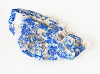 macro shooting of natural mineral - raw Lazurite (Lapis Lazuli) stone on white marble from Ural Mountains