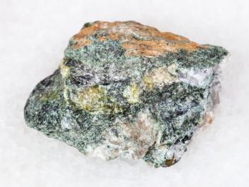 macro shooting of natural mineral - rough beryl rock on white marble from Ural Mountains