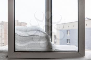 snowdrift between frames on balcony of residential house in Moscow city in winter