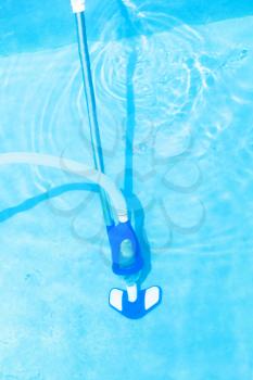 manually vacuum cleaning of outdoor swimming pool in summer day