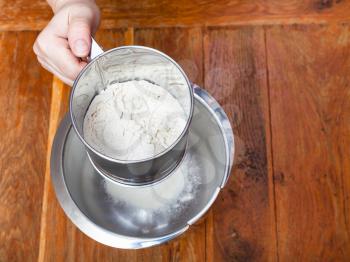 cooking of pie - sifting the flour through sifter into steel bowl