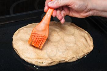 cooking of pie - oiling the crust of raw pie by silicone brush